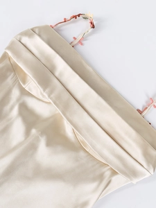 Détail de la robe en satin champagne avec broderies florales colorées sur les fines bretelles