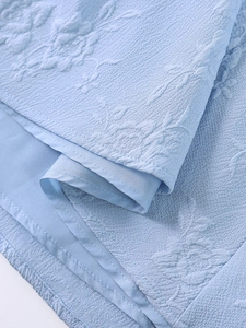 Détail du tissu jacquard bleu clair avec relief floral et doublure intérieure lisse