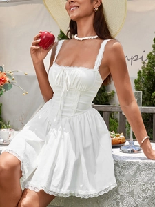 Detail of white mini dress featuring lace trim edges and a delicate front bow tie