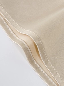 Gros plan sur le tissu en soie champagne avec bordure en dentelle et coutures fines