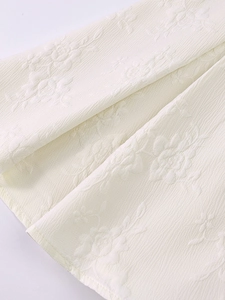 Détail macro du tissu jacquard blanc avec motifs de roses et texture plissée