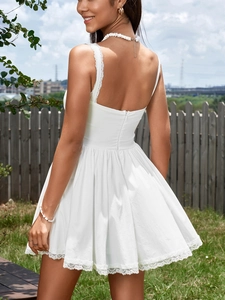 Detail of white mini dress featuring delicate lace trim on straps and hemline in a garden
