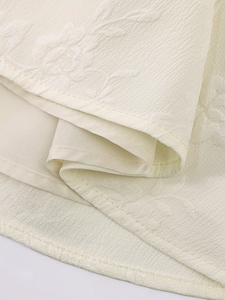 Vue détaillée en macro du tissu jacquard crème avec motifs de roses et doublure intérieure