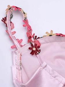 Détail d'une robe en satin rose avec broderie florale et doublure en maille fine