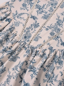 Detail of floral print dress featuring blue vintage pattern and ruffled lace neckline