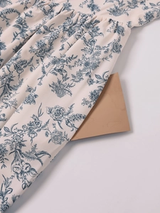 Detail of light beige floral dress fabric with elegant vintage prints and soft pleats