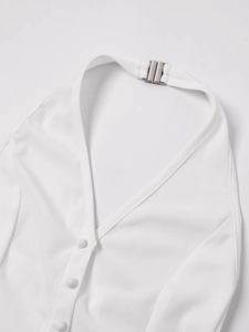Détail du haut dos nu blanc avec décolleté en V, boutons en tissu et boucle argentée