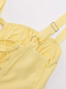 Detail view of yellow dress with adjustable straps, metal rings, and hidden zipper