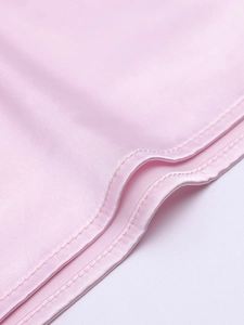 Vue détaillée du tissu en satin de soie rose avec coutures de qualité et texture lisse