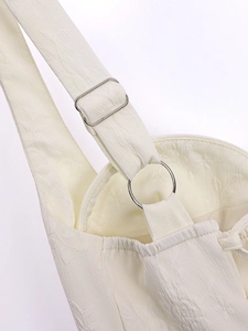 Détail de la bretelle réglable avec boucle argentée sur une robe en jacquard blanc