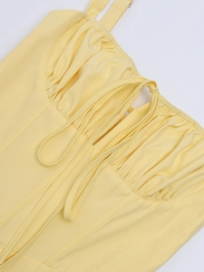 Detail of yellow dress with corset stitching, thin straps and drawstring tie front