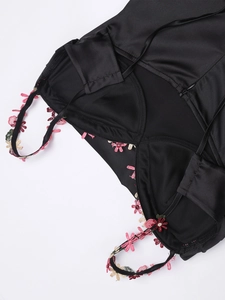 Détail de la robe en satin noir avec bretelles brodées et fermeture éclair invisible