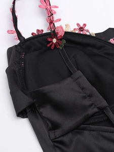 Détail de broderies florales sur robe en soie noire avec motifs de fleurs roses