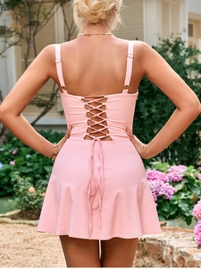 Detail of light pink mini dress showing back cross-tie design with gold adjustable rings
