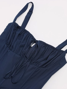Close-up of navy fishbone dress featuring ruched bust detail and lace-up straps