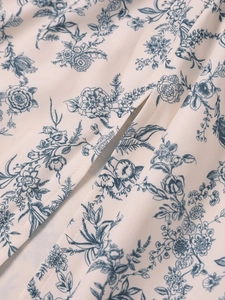 Macro detail of beige fabric with blue floral print showing side slit and neat stitching