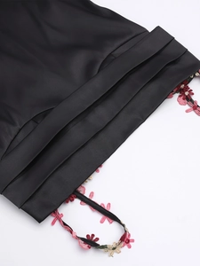Détail de robe en soie noire avec broderies florales 3D et plis élégants raffinés