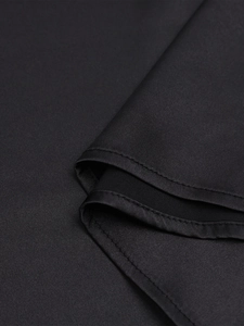 Gros plan détaillé du tissu noir lisse avec coutures doubles et texture soyeuse du vêtement