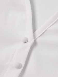 Détail du haut blanc à col en V montrant le tissu texturé et les boutons recouverts