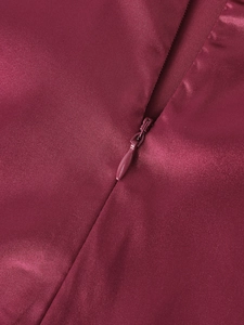 Détail de la fermeture éclair invisible sur une robe en satin bordeaux de haute qualité