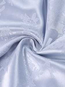 Macro shot of light blue floral jacquard satin fabric with elegant silk-like luster