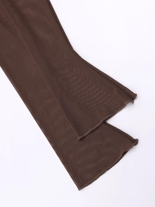 Detail view showing sheer mesh texture and flared hem of brown trousers