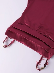 Détail d'une robe en satin bordeaux avec broderies florales délicates sur les bretelles