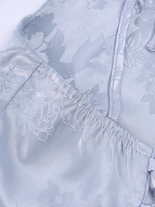 Macro shot of light blue floral jacquard fabric with elegant bird patterns and stitching