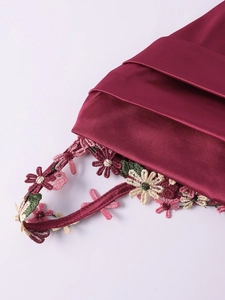 Détail de la robe en satin bordeaux avec broderie florale et plis horizontaux