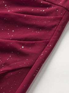 Gros plan du tissu en maille bordeaux avec paillettes argentées et détails plissés