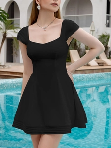 Detail of black square-neck mini dress with striped hem on a summer poolside background