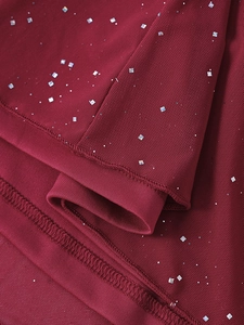 Dettaglio del tessuto a rete bordeaux con paillettes d'argento e cuciture delicate