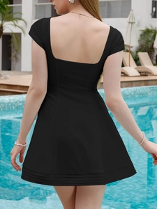 Detail of a black backless mini dress featuring a square neck and elegant ruffled hem