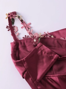 Détail d'une robe en satin bordeaux avec broderie florale 3D sur les fines bretelles