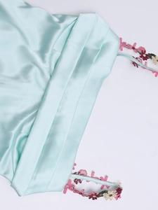 Vue détaillée d'une robe en satin vert menthe avec broderie florale et décolleté plissé élégant
