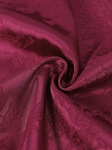 Close-up of luxury dark red jacquard fabric with elegant 3D floral texture and silk gloss