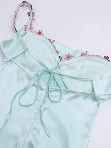 Détail de robe en satin menthe avec broderies florales et nœud élégant dans le dos