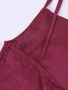 Close-up of wine red satin fabric with floral jacquard pattern and fine stitching details