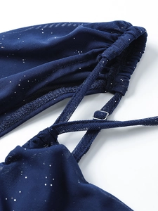 Détail macro de robe en tulle bleu foncé avec paillettes argentées et boucle de sangle réglable