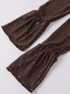 Dettaglio manica in tulle marrone con paillettes argentate e polsini a campana con volant