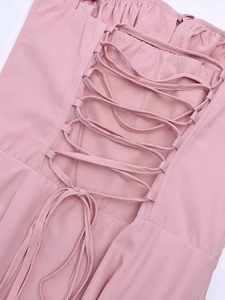 Close-up of the cross-strap tie and decorative bow on the back of the pink dress
