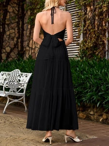 Detail of elegant black backless maxi dress featuring a chic bow tie and tiered ruffle skirt