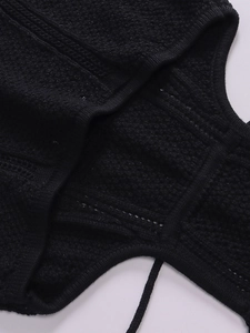 Detail shot of black knitted crochet fabric with intricate hollow mesh texture and craftsmanship