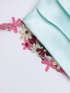 Détail de robe en satin bleu clair avec broderie florale fine et dentelle de soie
