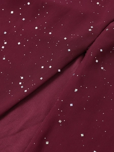 Détail macro du tissu en maille bordeaux avec paillettes argentées et poudre scintillante