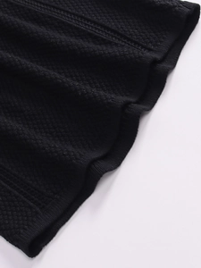 Close-up of black honeycomb knit fabric and ribbed hem on the maxi dress