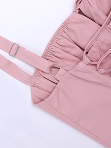 Detail of light pink dress featuring adjustable straps with silver buckles and elastic pleats