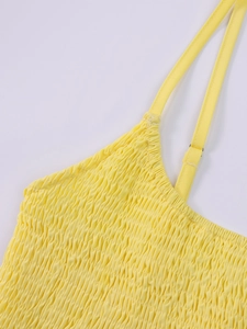 Close-up of vibrant yellow smocked fabric with delicate adjustable thin straps