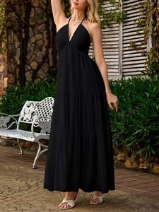 Detail of elegant black deep V neck halter backless tiered maxi dress in outdoor setting