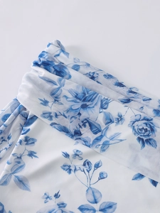 Detail of white mesh dress featuring blue floral print and delicate gathered pleats